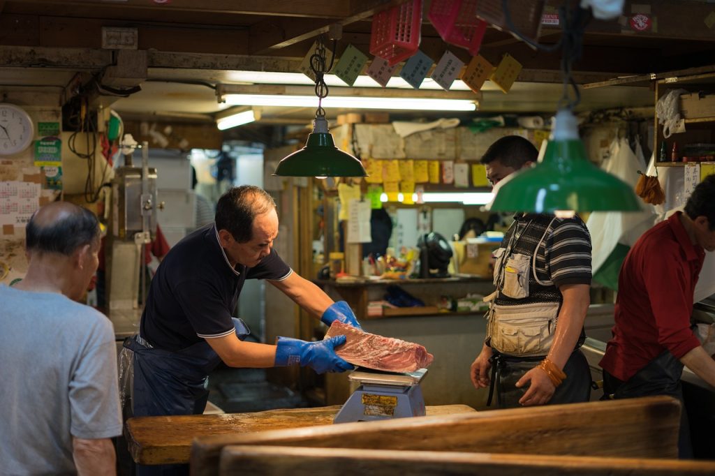 Vendedor de atún pesando el pescado en una báscula en el mercado de Tsukiji, Tokio, Japón